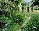 The pathway meanders through the traditional stone and rafter pergola